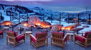 a fire pit with chairs and a snowy mountain in the background
