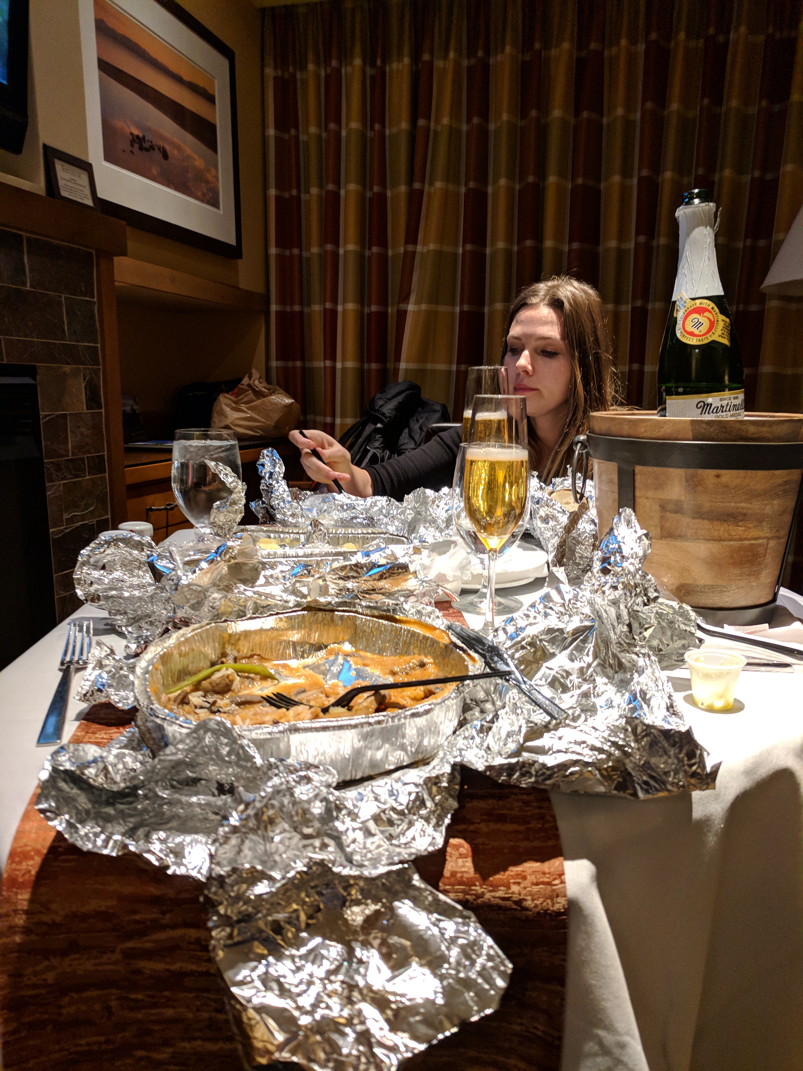 a woman sitting at a table with foil wrapped food