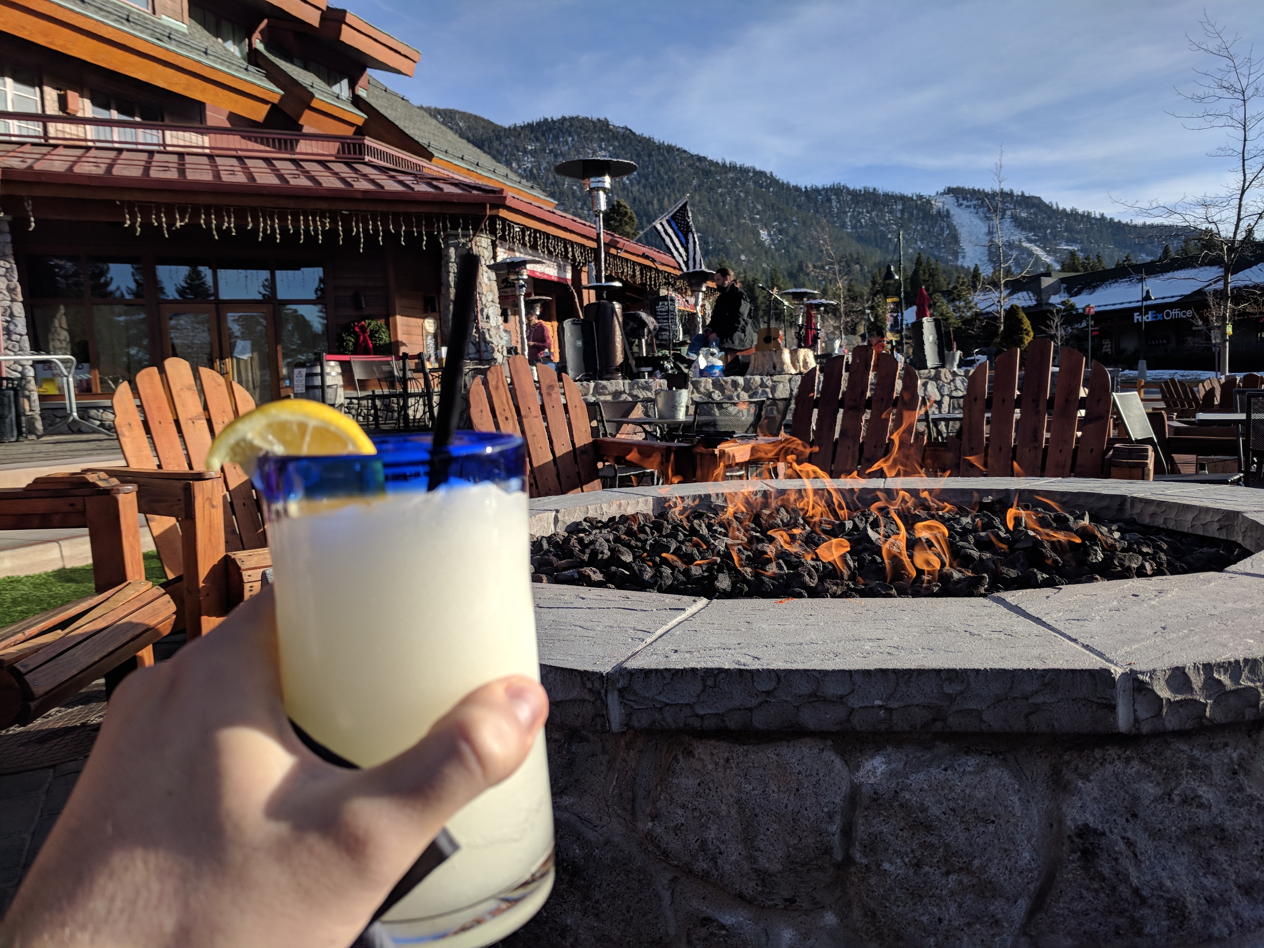 a hand holding a glass of milk with lemons in front of a fire pit